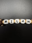 Nahaufnahme der personalisierten Schnullerkette Bär mit Namen von BabyLions® mit weißen Namensperlen, naturfarbenen Holzlinsen und Silikonperlen in Braun- und Beigetönen