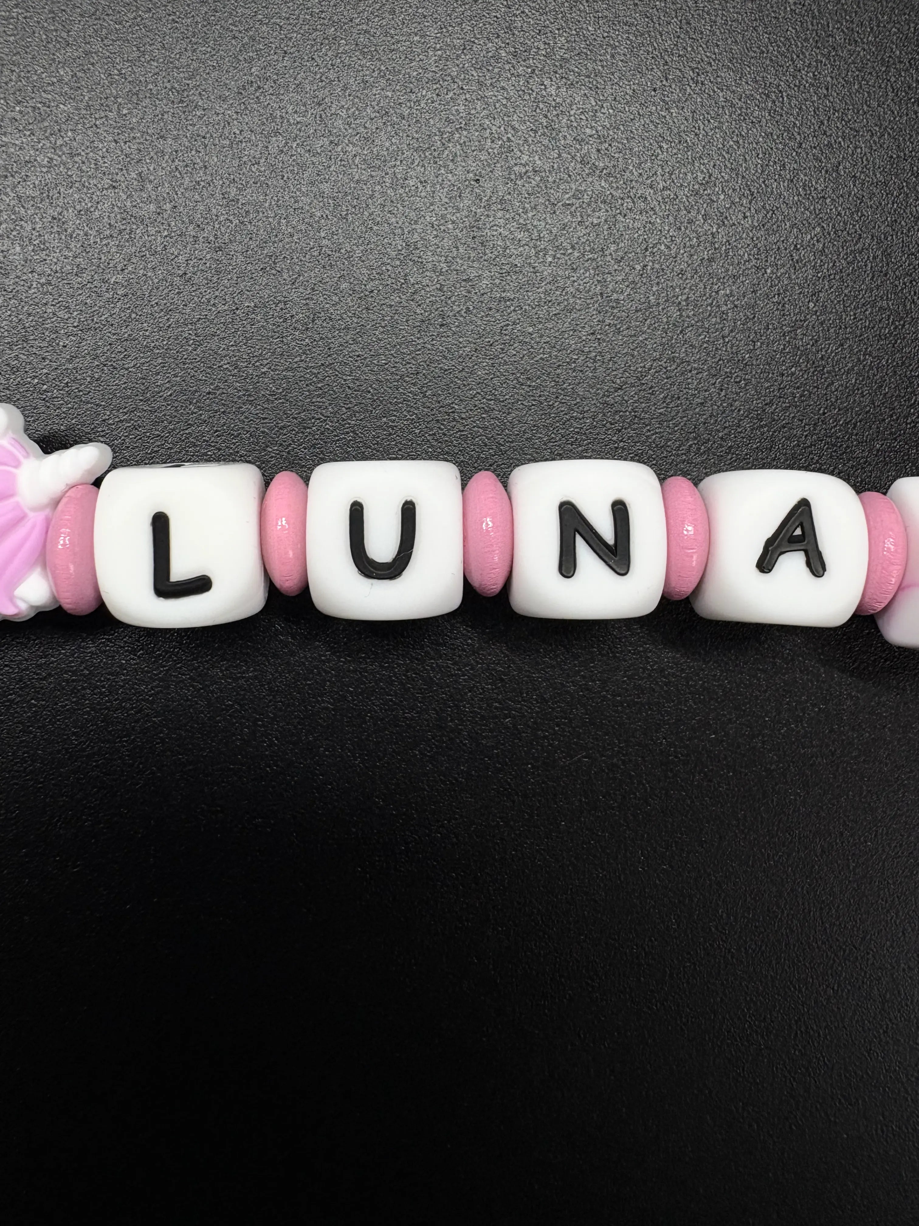 Detailaufnahme der personalisierten Schnullerkette mit dem Namen Luna in Rosa und Weiß