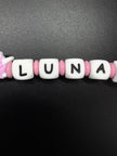 Detailaufnahme der personalisierten Schnullerkette mit dem Namen Luna in Rosa und Weiß