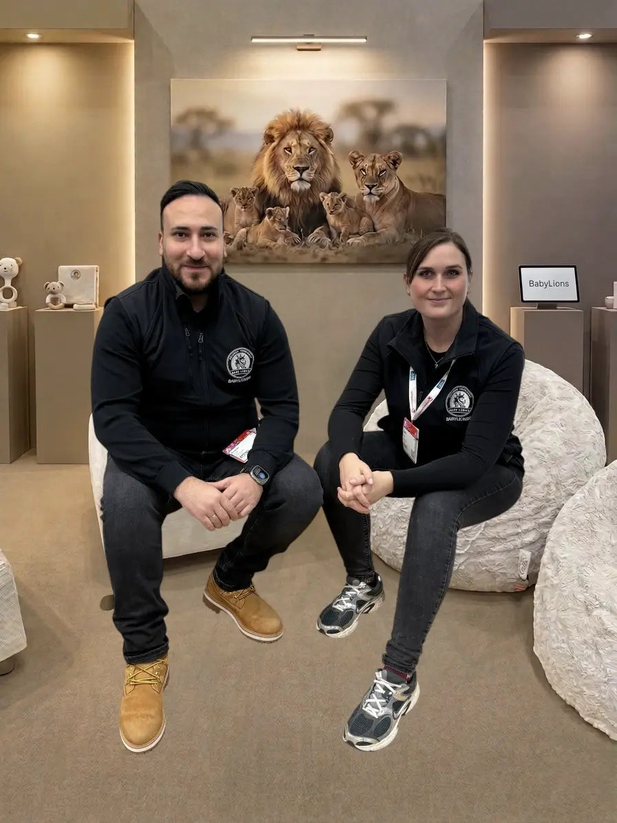 Die Gründer von BabyLions® sitzen gemeinsam in einem modernen Showroom vor einem Löwenbild und lächeln in die Kamera