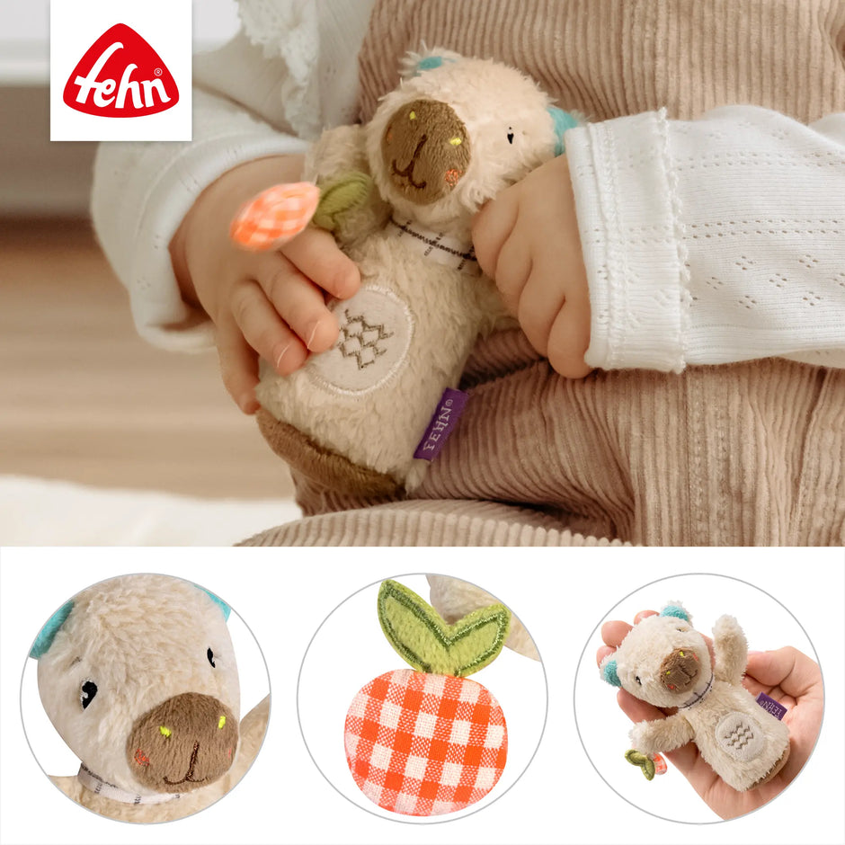Baby hält eine Mini Rassel Capybara aus weichem Plüsch mit Greifelement und kleinen Details, ideal für kleine Hände