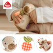 Baby hält eine Mini Rassel Capybara aus weichem Plüsch mit Greifelement und kleinen Details, ideal für kleine Hände