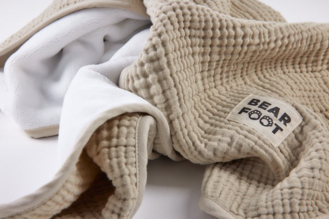 Detailaufnahme der sandfarbenen Musselin-Babydecke mit weicher Fleece-Rückseite und hochwertigem BEARFOOT-Label – kuschelig, atmungsaktiv und ideal für Babys