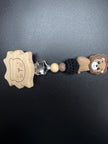 Detailaufnahme der personalisierten Schnullerkette Simba mit Holzclip, Löwenmotiv und gehäkelter schwarzer Perle