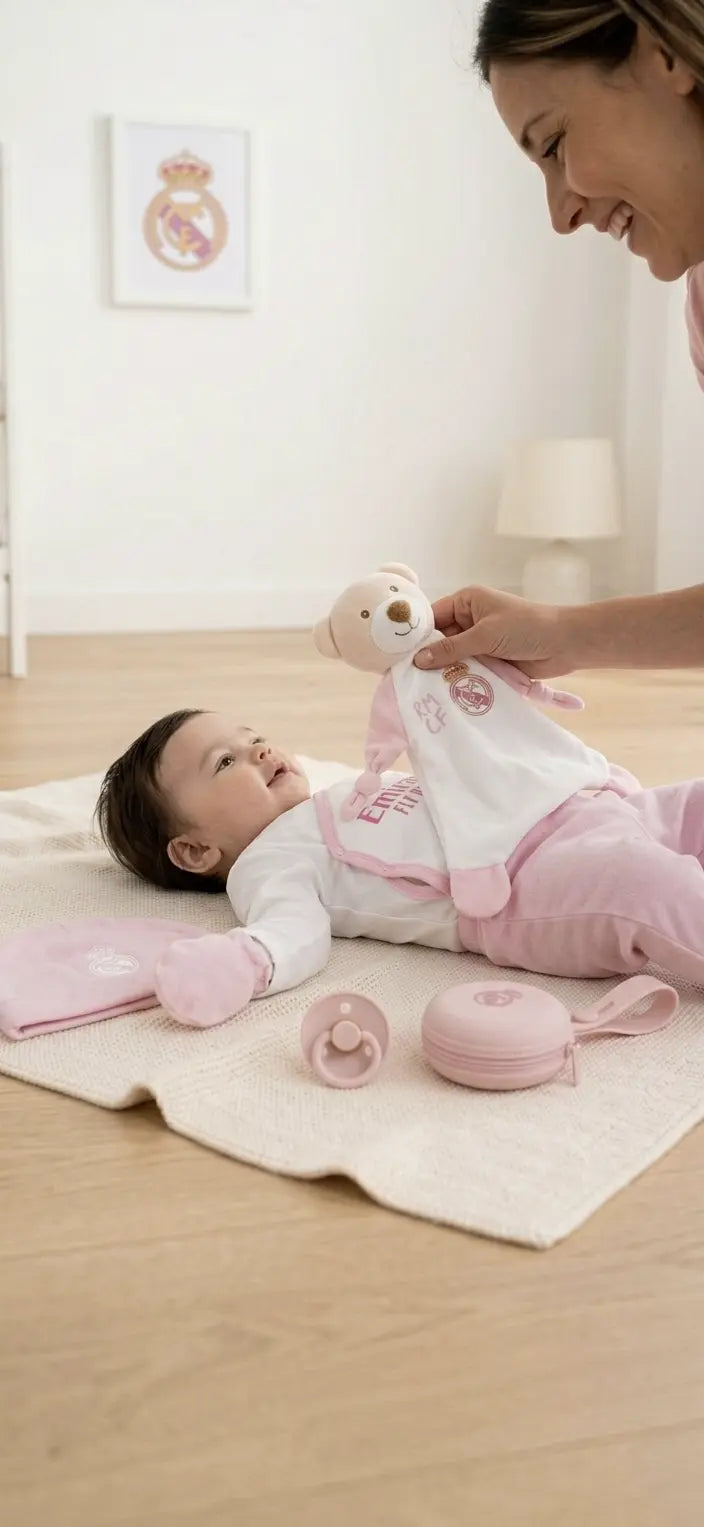 Baby mit Real Madrid Newborn Premium Bundle in Rosa auf Spieldecke mit Schmusetuch, Schnuller, Schnullerhalter und Baby-Erstausstattung – offizielles Real Madrid Lizenzprodukt von BabyLions®
