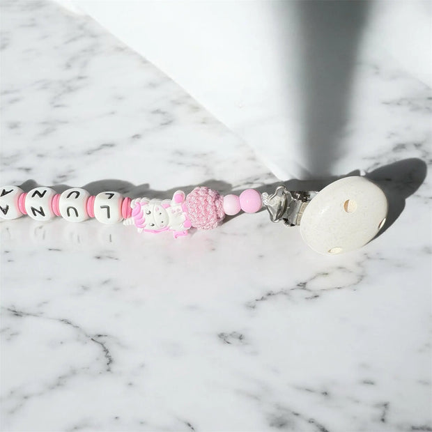 Nahaufnahme einer personalisierten Schnullerkette im Einhorn-Design in Rosa mit Clip und Perlen