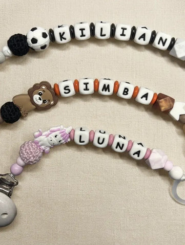 Drei handgemachte personalisierte Schnullerketten von BabyLions® mit den Namen Kilian, Simba und Luna auf hellem Hintergrund