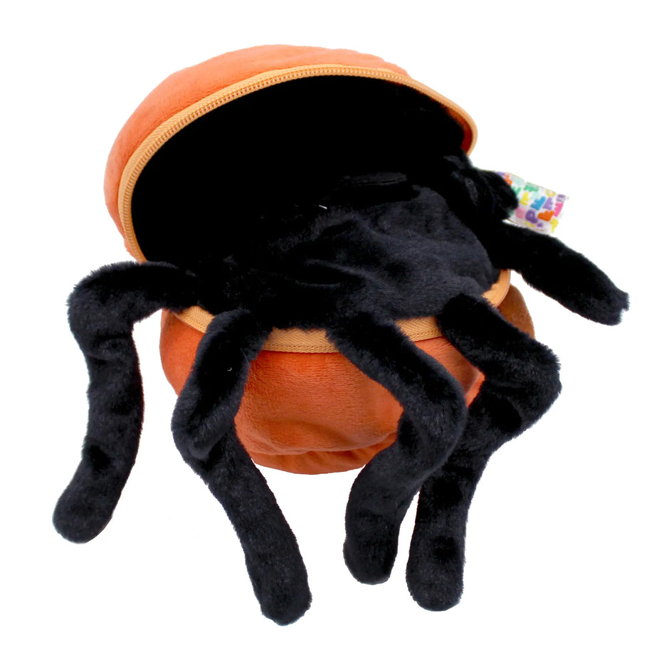 Schwarze Plüschspinne kommt aus orangefarbenem Kürbis Kuscheltier heraus